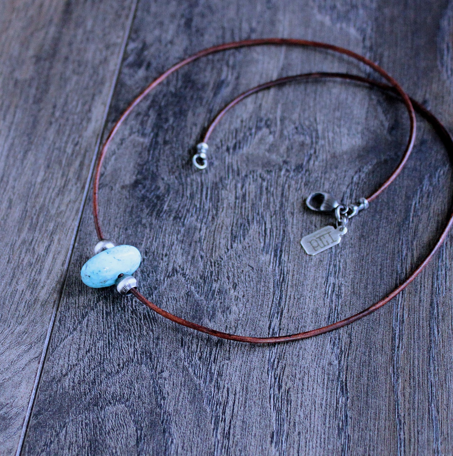 large turquoise bead on leather cord